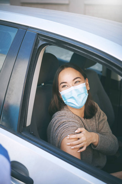 全ての予防接種は。覆面の若い女性がセンターを通って車の中でCovid-19テストを受けて - 写真・画像