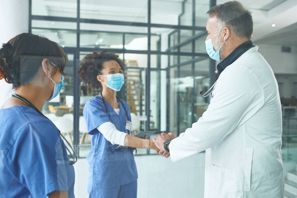 Συγχαρητήρια για την προαγωγή σου. ένας όμορφος ώριμος γιατρός στέκεται και σφίγγει το χέρι μιας νοσοκόμας στην κλινική - Φωτογραφία, εικόνα