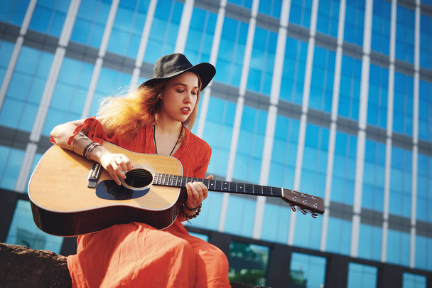 Did you know that your guitar keeps the bad days at bay. a beautiful young woman playing the guitar while out in the city - 写真・画像