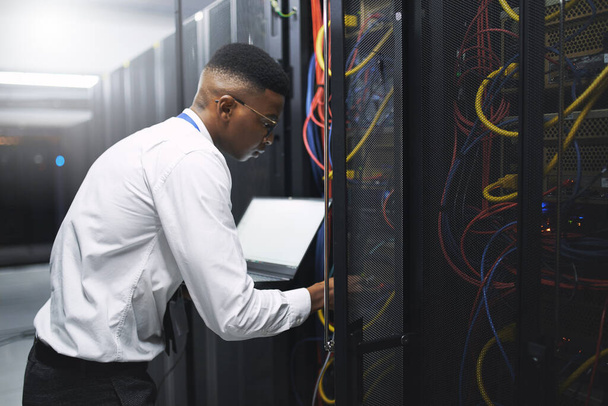 Plug into a higher level of security. a young male technician working in a server room - Photo, Image
