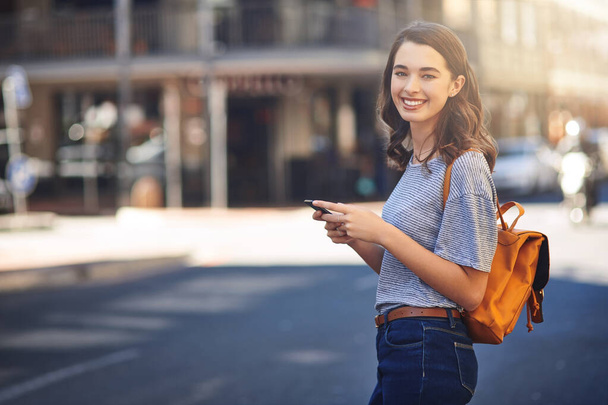 Im on the way to meet my friends. Cropped portrait of an attractive young woman sending text messages while spending her day out in the city - Photo, Image