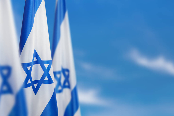 Israel flag with a star of David over cloudy sky background. Patriotic concept about Israel with national state symbols. Banner with place for text. - Fotografie, Obrázek