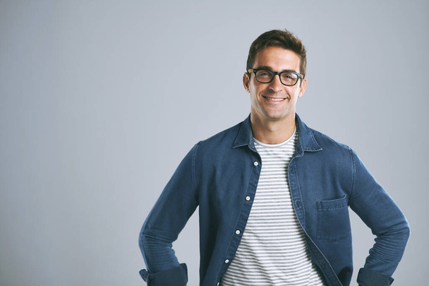 Good glasses make you feel more confident. a handsome man posing against a grey background - Foto, afbeelding