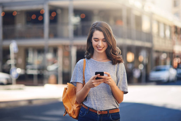 Изучение города с помощью технологий. привлекательная молодая женщина отправляет сообщения, проводя свой день в городе - Фото, изображение