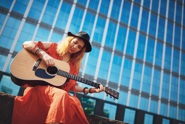 Theres no better medicine for a bad day. a beautiful young woman playing the guitar while out in the city - Foto, immagini