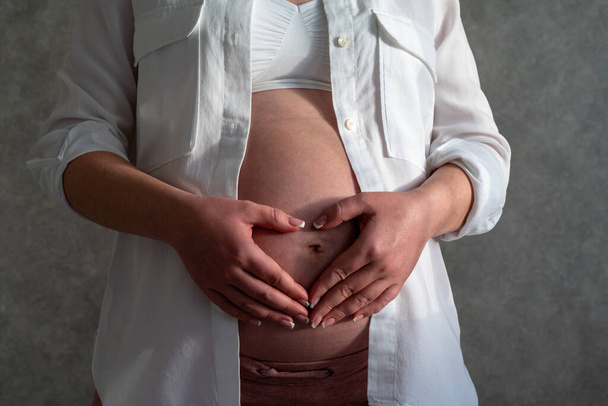 Έγκυος κοιλιά γυναίκας. Έννοια εγκυμοσύνης. Mid-section πορτρέτο αγνώριστη γυναίκα κατά τη διάρκεια των τελευταίων μηνών της εγκυμοσύνης - Φωτογραφία, εικόνα