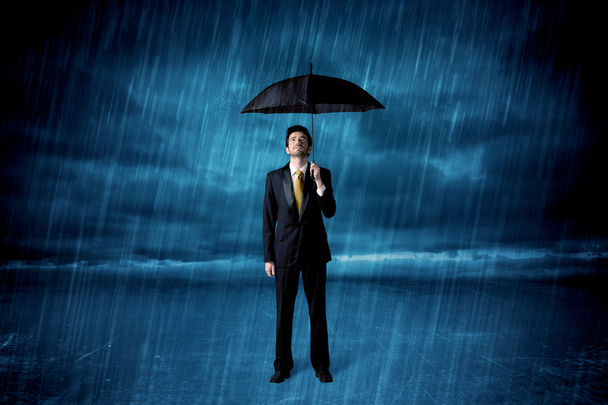 Business man standing in rain with an umbrella - Fotografie, Obrázek