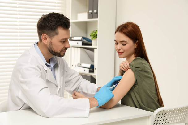 Doctor giving hepatitis vaccine to patient in clinic - Photo, image
