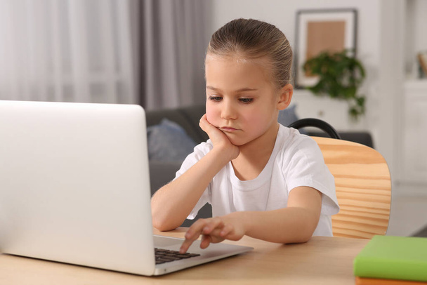 Little girl using laptop at table indoors. Internet addiction - Foto, immagini