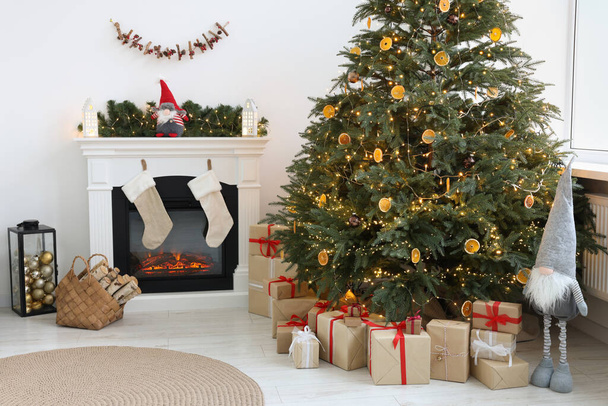 Many different gift boxes under Christmas tree and festive decor in living room - Φωτογραφία, εικόνα
