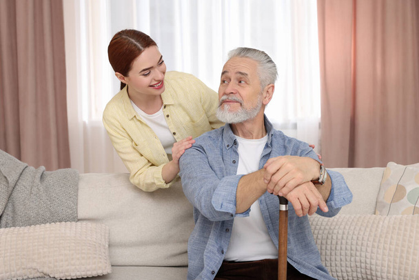 Caregiver and senior man with walking cane at home - Foto, Imagen