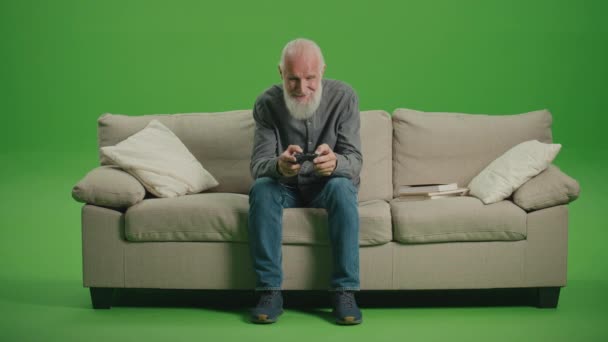 Vihreä näyttö. Vanha harmaapartainen mies pelaa tietokonepelejä joystickillä. Vanhempi mies pelaa PlayStation.Tech Nostalgia ja sukupolvien jako. - Materiaali, video