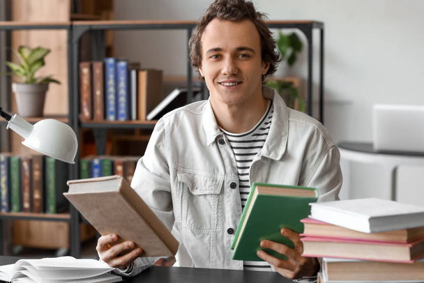 Young man with books sitting at table in library - Photo, Image