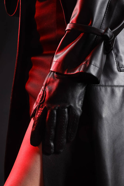 Attractive young woman in leather glove on dark background, closeup - 写真・画像