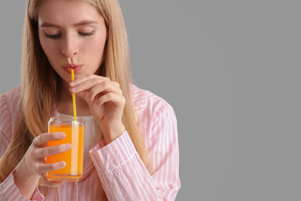 Mujer joven bebiendo jugo de verduras sobre fondo gris, primer plano - Foto, Imagen