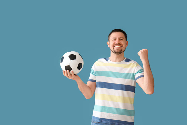 Hombre feliz con pelota de fútbol sobre fondo azul - Foto, Imagen