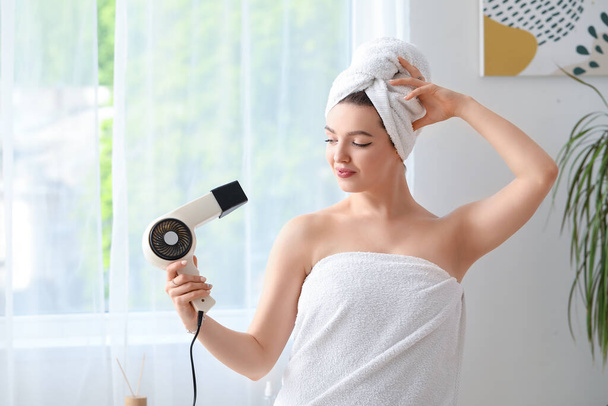 Pretty young woman with hair dryer in bathroom - Foto, Imagem