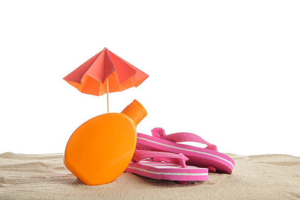 Composition créative avec bouteille de crème solaire, mini parapluie et tongs sur sable isolé sur fond blanc - Photo, image