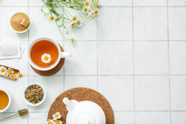 Cup of hot chamomile tea on white tile background - Photo, Image
