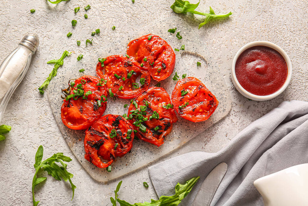 Board with tasty grilled tomatoes and green onion on grey background - Photo, Image