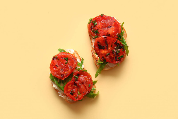 Sandwichs aux délicieuses tomates grillées et roquette sur fond jaune - Photo, image