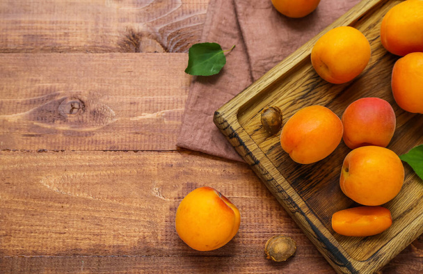 Board with fresh apricots on wooden table - Foto, imagen