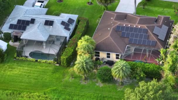 きれいな生態系の電気エネルギーを生成するための青い太陽光発電パネルと典型的なアメリカの建物の屋根の空中ビュー。退職所得の概念のための再生可能エネルギーへの投資. - 映像、動画