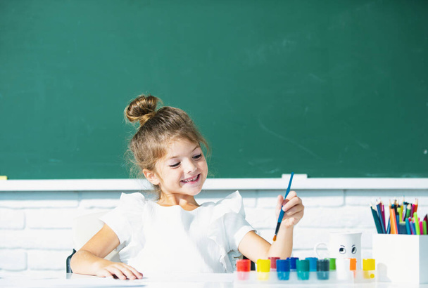 Funny school girl pupil drawing a picture. Cute little preschooler child drawing at school - Foto, afbeelding