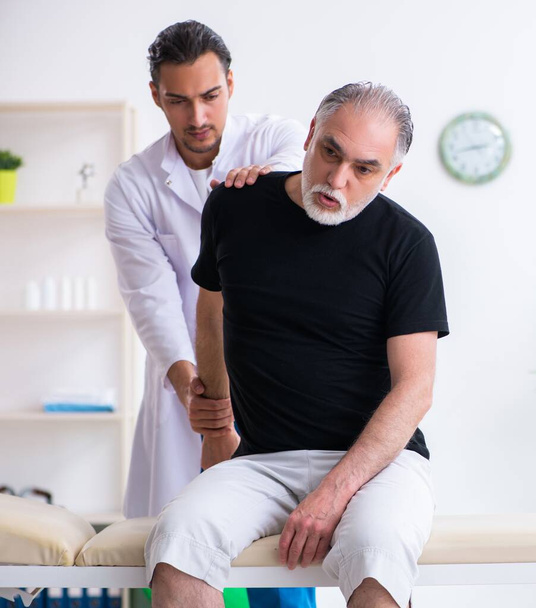 The old injured man visiting young doctor - Photo, Image