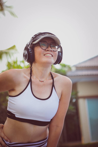 asiatico donna indossare cuffie mentre mattina esercizio a casa con felicità faccia  - Foto, immagini