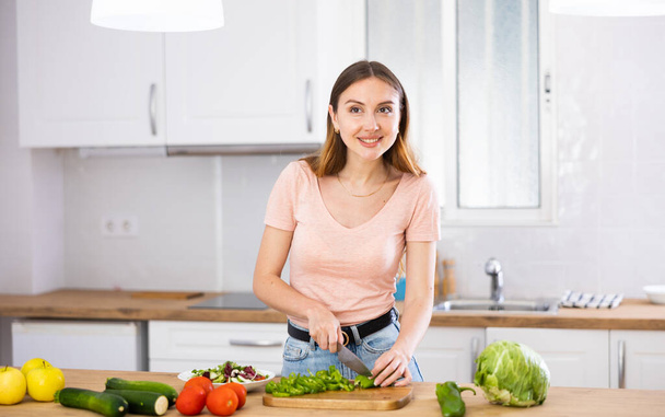 Housewife is cooking salad and cutting vegetables in the kitchen at her home. - Foto, Bild