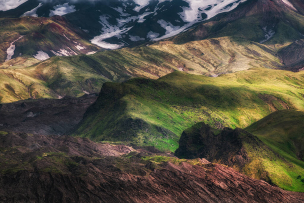 Green grass and snow on the rocks of Tolbachik volcano, Kamchatka, Russia. Summer nature abstract background - Photo, image