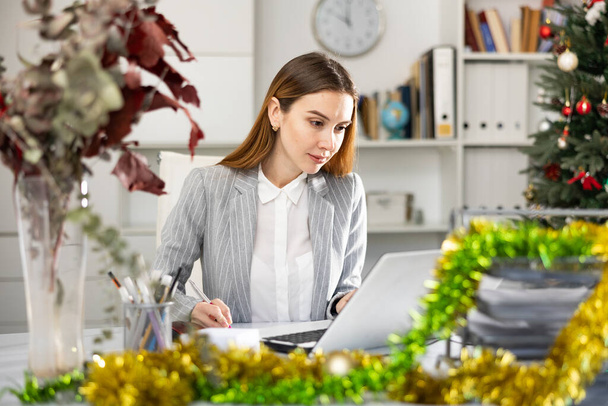 Успішна бізнес-леді використовує ноутбук на робочому місці під час Різдва
 - Фото, зображення