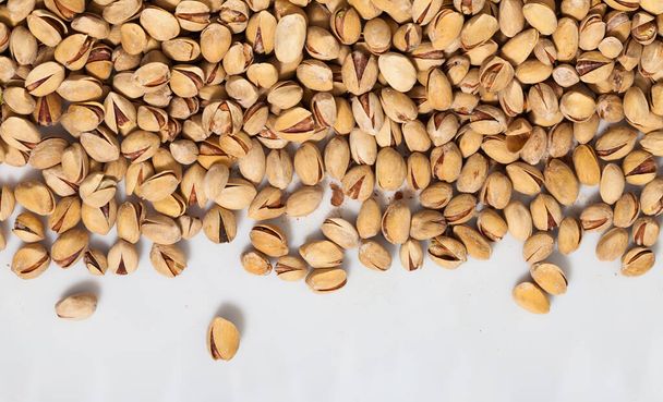 Natural background of unshelled roasted pistachio nuts on white background. Healthy snack.. - Valokuva, kuva
