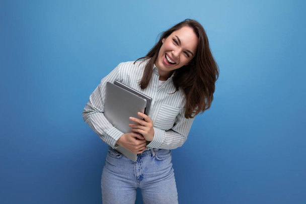 IT-Spezialist 25-jährige brünette Frau in Hemd und Jeans genießt es freiberuflich, einen Laptop in der Hand zu halten. - Foto, Bild