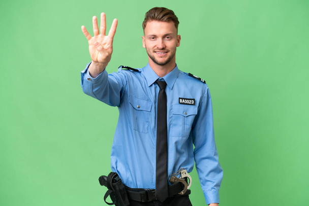 Jonge politieman over geïsoleerde achtergrond gelukkig en tellen van vier met vingers - Foto, afbeelding
