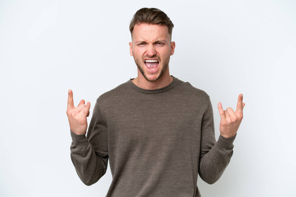 Young blonde caucasian man isolated on white background making horn gesture - Foto, afbeelding