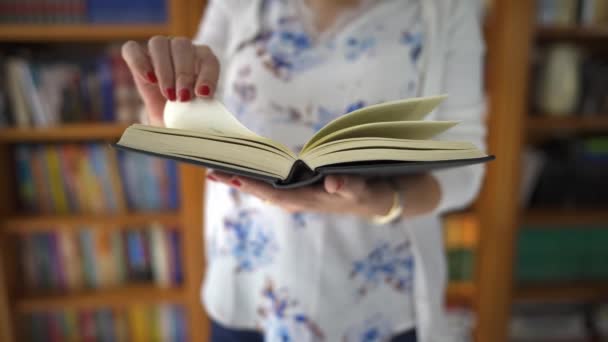 Vrouw die een boek leest en de pagina 's voor een boekenwinkel vol kopieën draait - Video