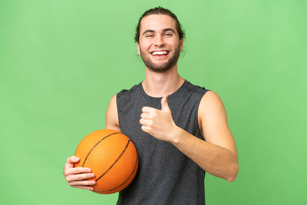 Jeune joueur de basket-ball homme sur fond isolé donnant un pouce geste - Photo, image