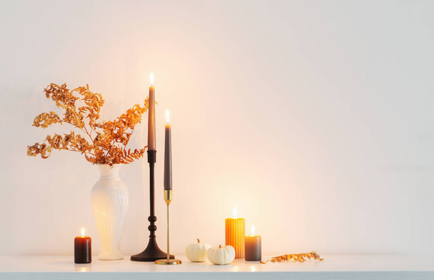 beautiful autumn home decor with burning candles in white interior - Photo, image