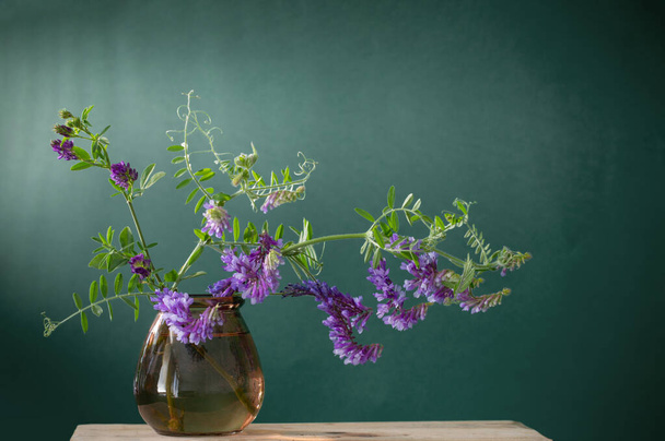wild purple flowers in glass vase on green background - Fotoğraf, Görsel