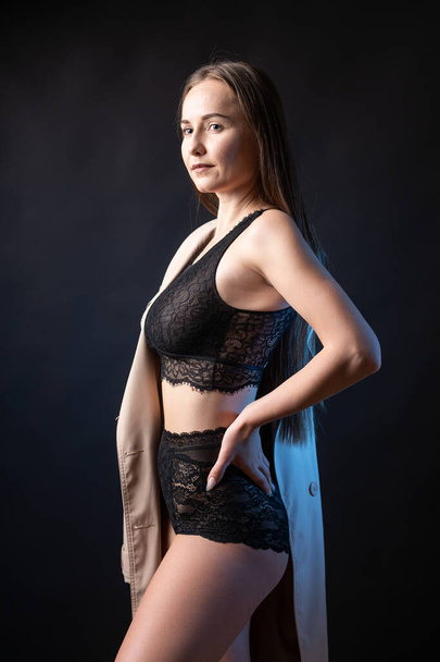 Studio portrait of a young slender girl in lingerie against a black background. - Photo, Image