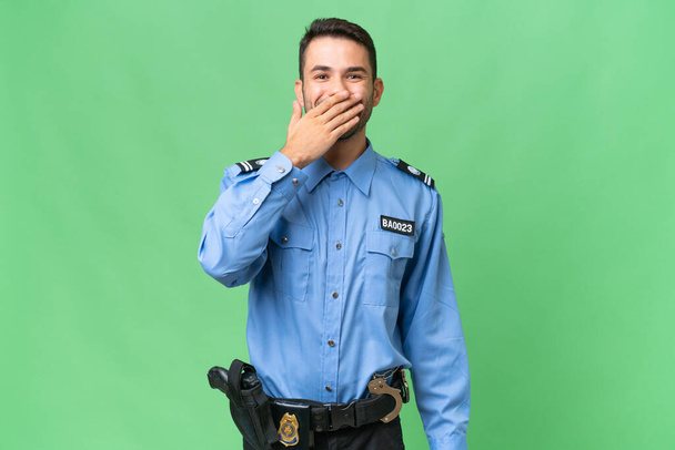 Junge Polizei kaukasischen Mann über isolierten Hintergrund glücklich und lächelnd bedeckt Mund mit der Hand - Foto, Bild