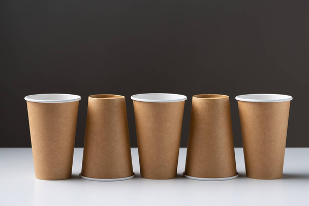 Disposable cardboard biodegradable cups on a white table, gray background. - Fotografie, Obrázek