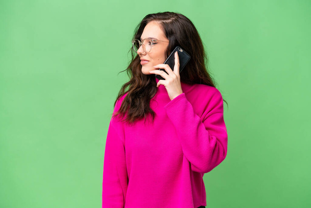 Νεαρή καυκάσια γυναίκα απομονωμένη σε απομονωμένο φόντο κρατώντας μια συνομιλία με το κινητό τηλέφωνο με κάποιον - Φωτογραφία, εικόνα
