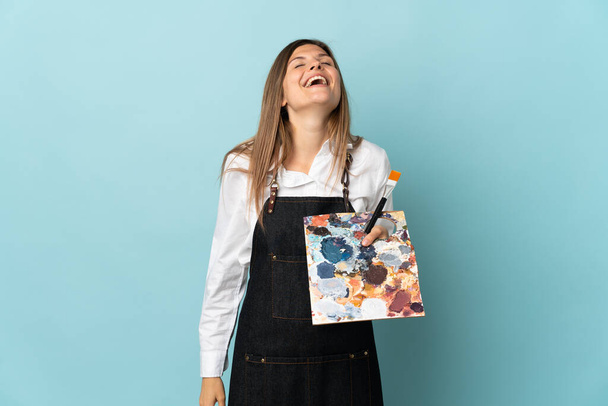 青を背景に孤立した若いアーティストスロバキア人女性が笑って - 写真・画像