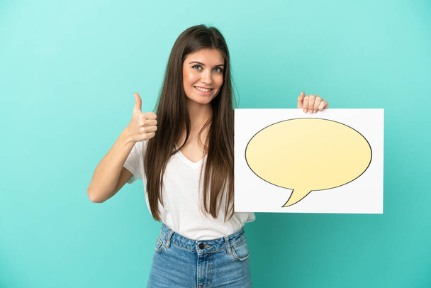 Young caucasian woman isolated on blue background holding a placard with speech bubble icon with thumb up - Photo, Image