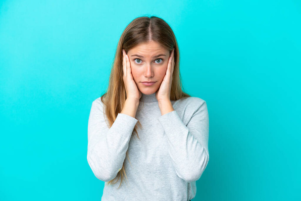 Junge blonde Frau isoliert auf blauem Hintergrund frustriert und mit verdeckten Ohren - Foto, Bild