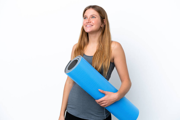 Young sport woman going to yoga classes while holding a mat thinking an idea while looking up - Photo, image