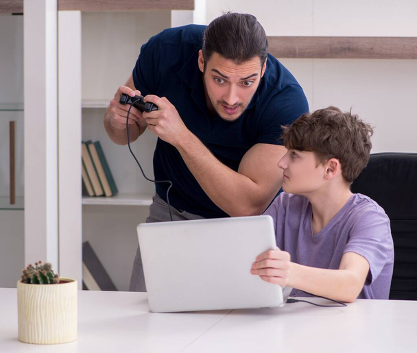 父と学校の少年は自宅でコンピュータゲームをプレイ - 写真・画像